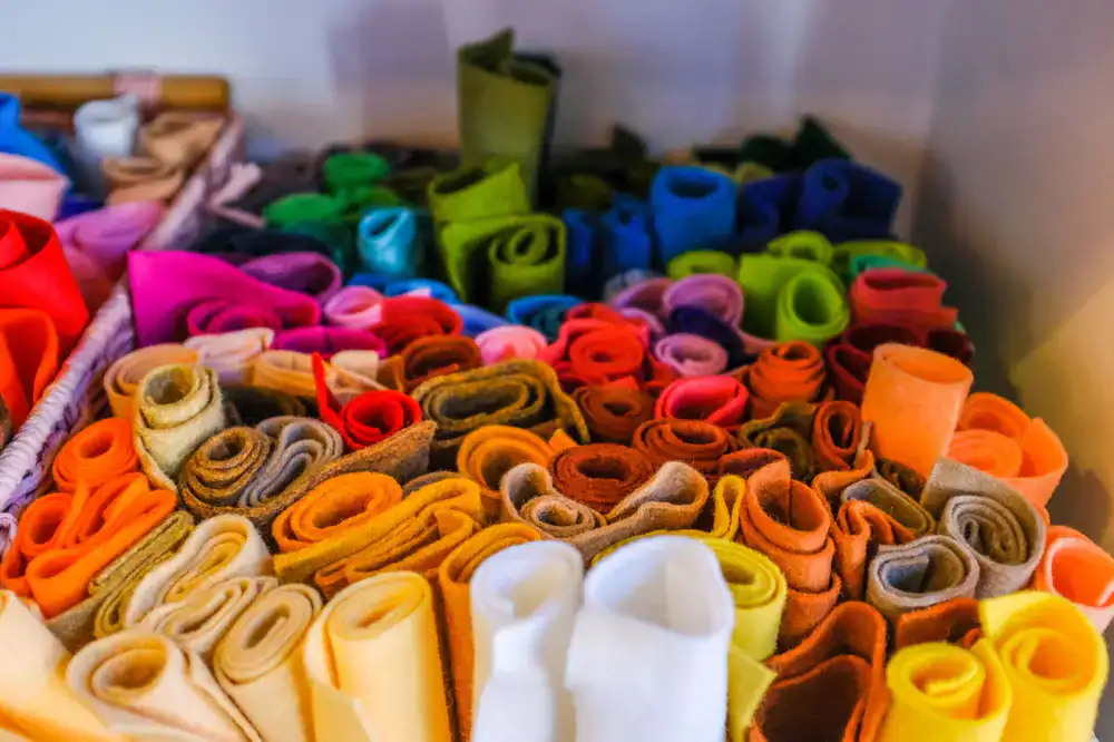 Assortment of colorful felt bodies and silk ribbons on a cutting table