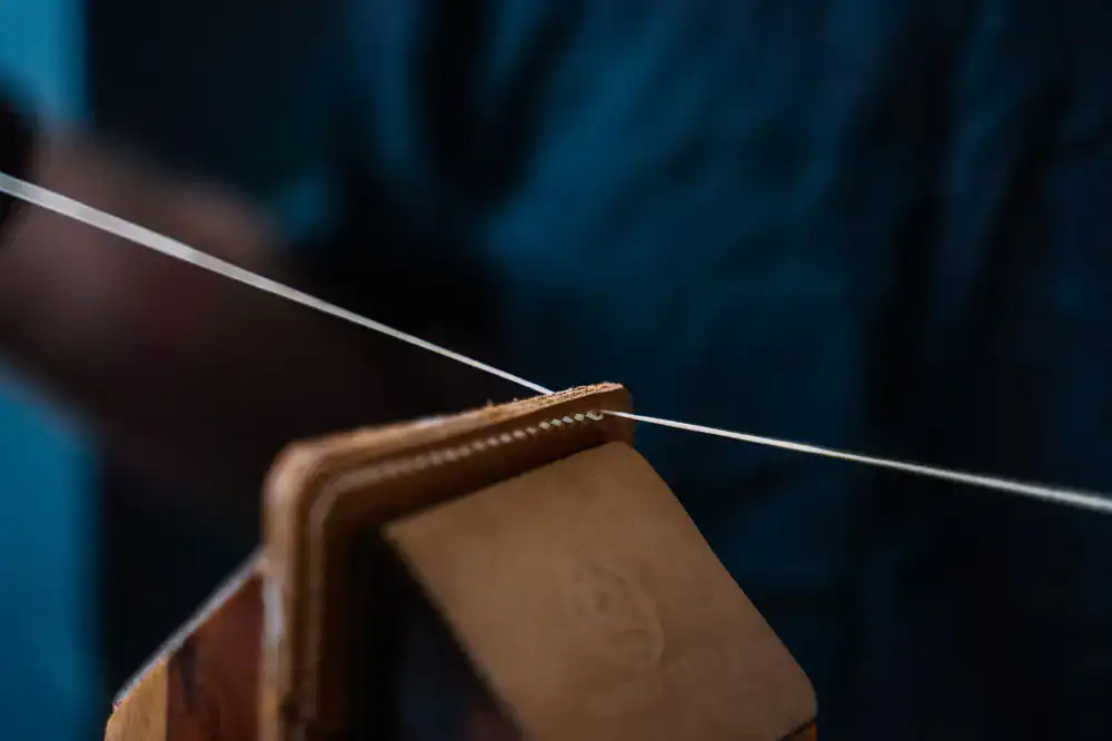 Close-up of hand-stitching a leather sweatband into the interior of a bespoke hat