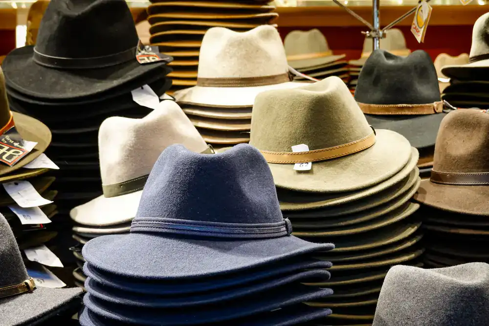 A row of classic fedoras and wide-brimmed hats on a vintage wooden shelf