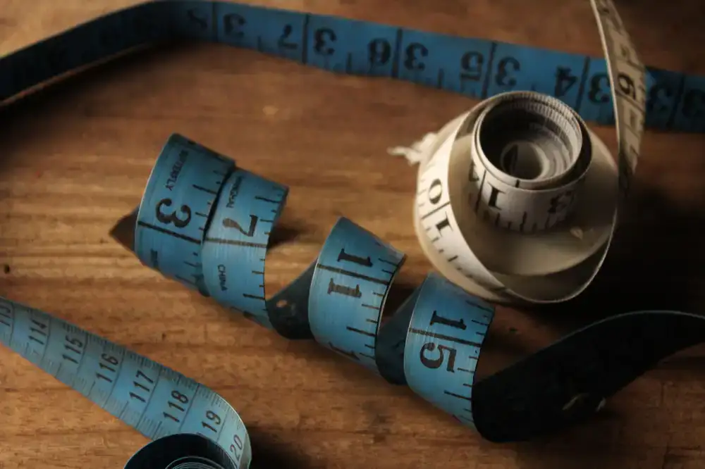 A tailor's measuring tape draped over a wooden hat block